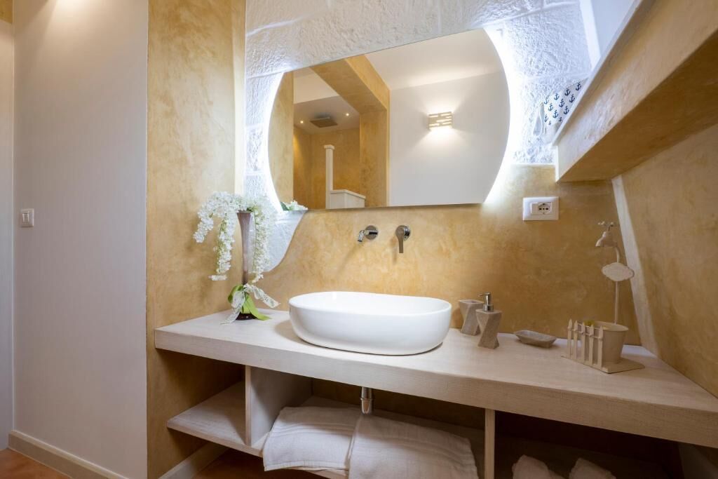 Un baño con un espejo grande, un lavabo blanco y un perchero para toallas.