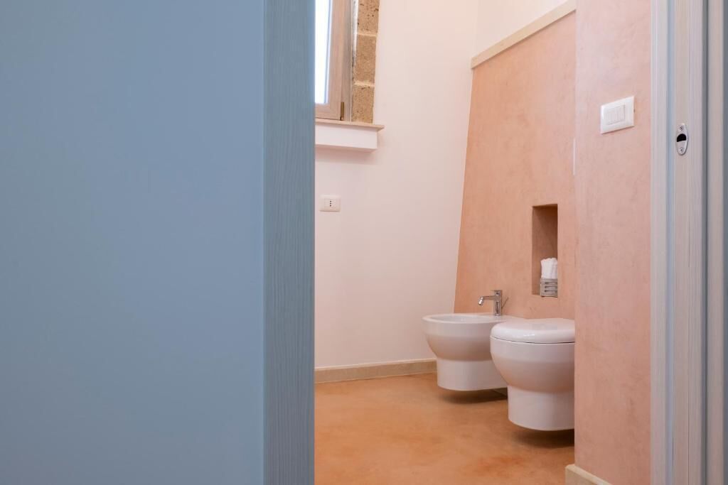 Un baño con inodoro, bidé y una ventana sobre el lavabo.