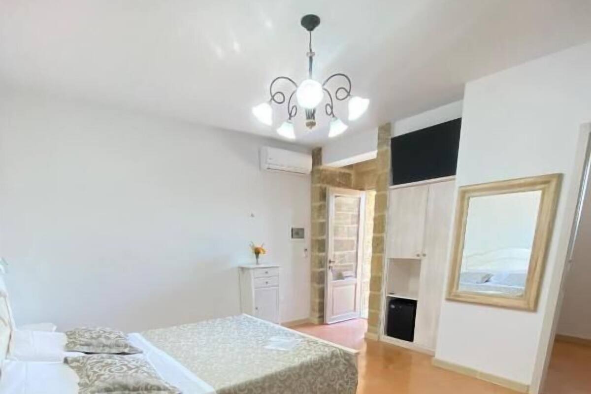 Un dormitorio con cama, escritorio, silla, armario y ventana.