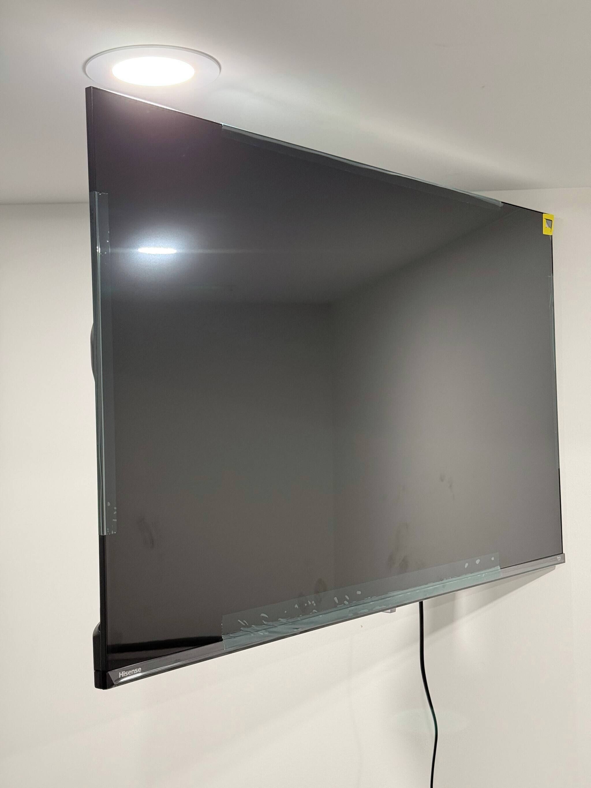 Een grote, lege wandtelevisie met een zichtbare stroomkabel.