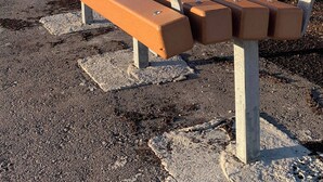 A park bench with a metal backrest and armrests, set on a gravel surface. - Room-haven in the Prairies 1BR B (Winnipeg)