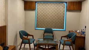 A conference room with a glass table, four chairs, a wooden desk, and a patterned window blind. - Sanskar Grand by Maan (Jaipur)