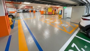 Ett parkeringshus med flera våningar, tydliga skyltar som visar vägen, en självbetjäningskiosk och en bil som står parkerad på en anvisad plats.