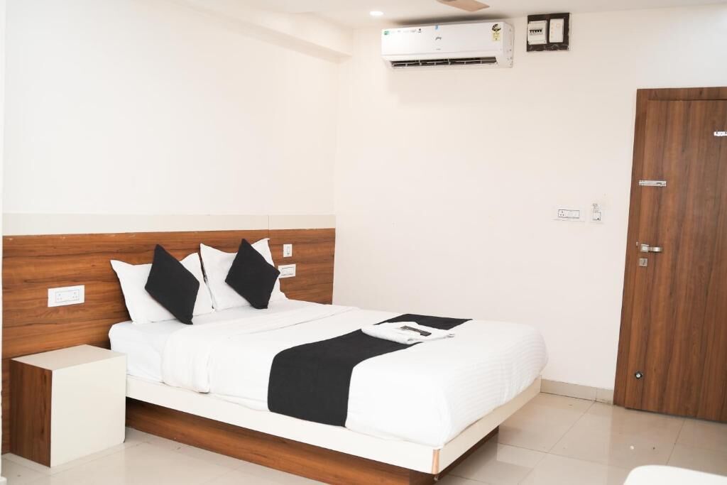Una habitación de hotel con cama, mesita de noche, armario y unidad de aire acondicionado.