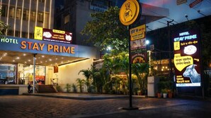 Un hotel llamado 'Stay Prime', con letrero, entrada y follaje circundante.
