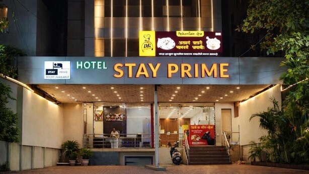 Entrada de hotel con un letrero que dice 'STAY PRIME' y un letrero que indica 'HABITACIÓN PRIME DISPONIBLE'.