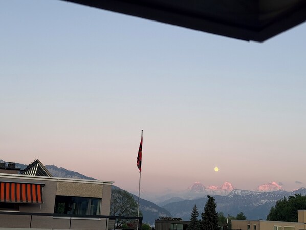 Un bâtiment orné d’un mât de drapeau, doté d’une architecture moderne et ayant une chaîne de montagnes en toile de fond.