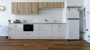 A modern kitchen with white cabinets, a wooden upper section, a built-in dishwasher, and a white refrigerator.