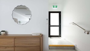 A staircase with yellow edges, a wooden dresser, a mirror, and a door with an emergency exit sign.
