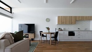 A modern kitchen with white cabinets, a dining table, and chairs.