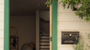 Une entrée d’immeuble avec une porte verte, une boîte aux lettres portant l’inscription « 110 W PEARL », et un escalier menant à l’intérieur.
