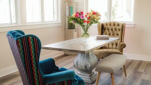 Une pièce comprenant une table à manger, deux chaises, un vase avec des fleurs et une bibliothèque.