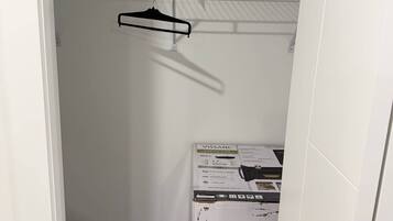 A narrow hallway with a white door frame, a metal rack with a black hanger, and a white box with text and images on it.