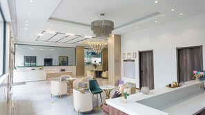 En modern hotellobby med en receptionsdisk, en sittgrupp och en stor spegel.
