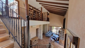 Un intérieur à plusieurs niveaux comprenant un escalier, des étagères, un coin salon et une cheminée.