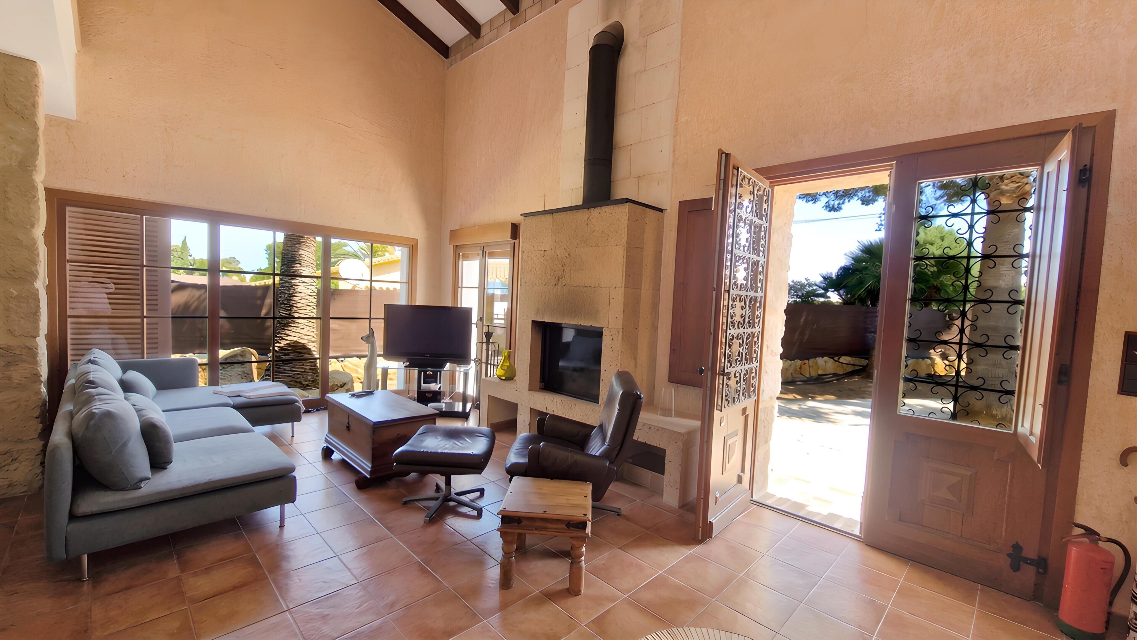 A spacious living room with a fireplace, a sofa, a TV, and a dining area.