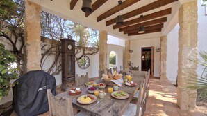 Une table à manger en bois, avec des aliments pour le petit-déjeuner, un porte-manteau et une horloge au mur.