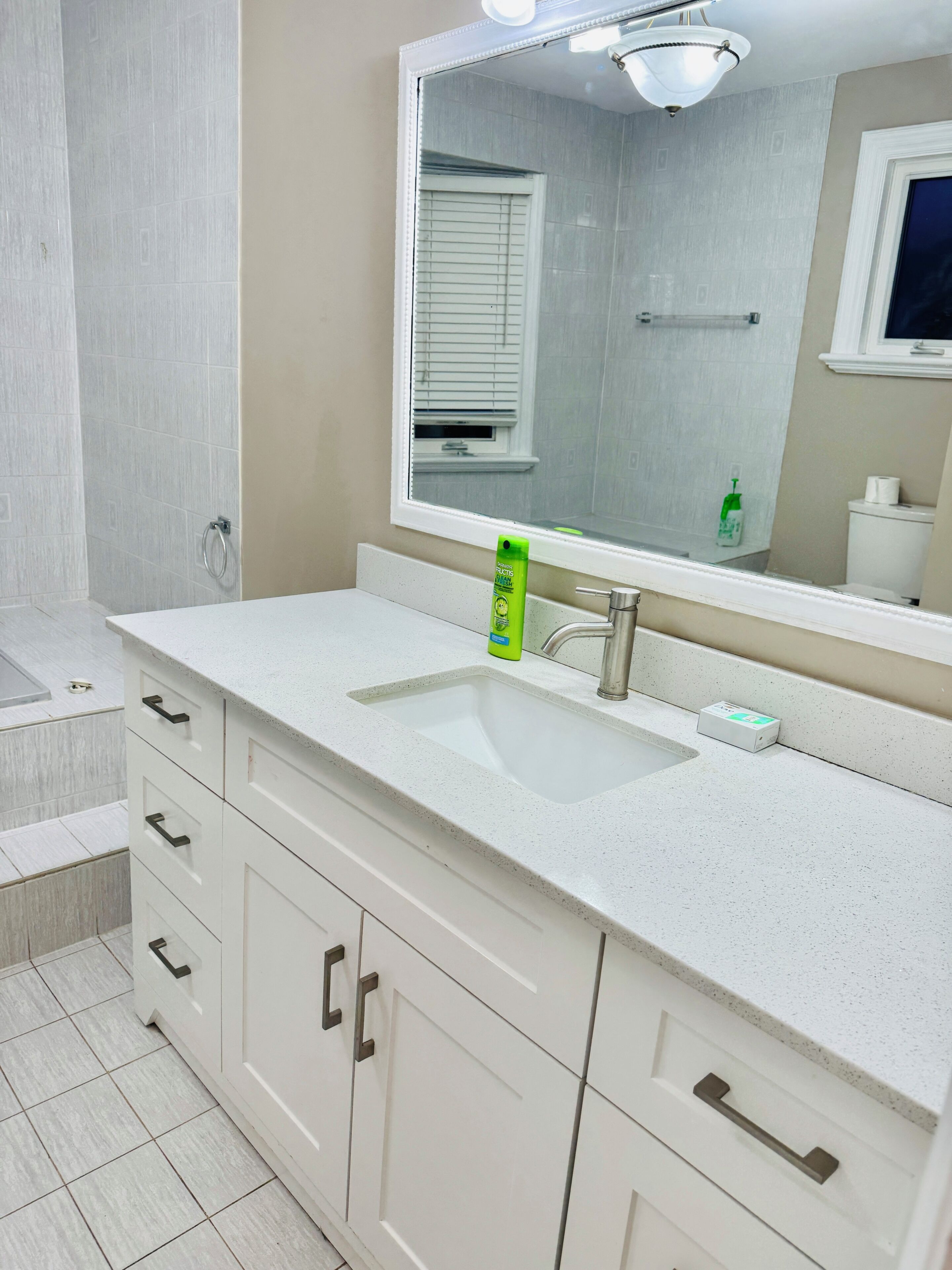 A bathroom with a white sink, mirror, and cabinets.