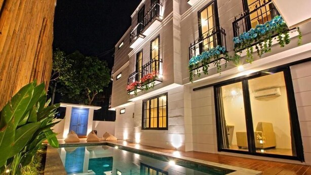 A modern building with a swimming pool, balconies with flower boxes, and a well-lit exterior. - Pamela Bali (Keroboken Kelod)