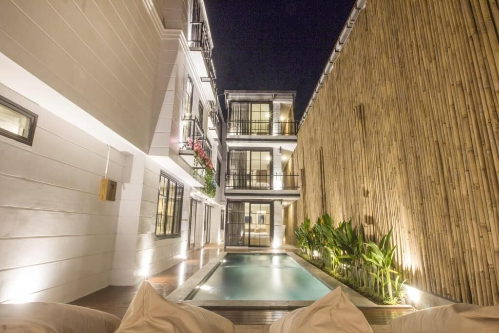 A modern building with a pool, balconies, and a bamboo wall.