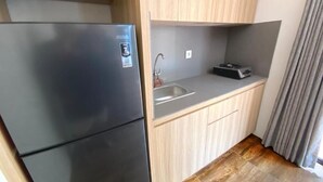 A compact kitchen with a black refrigerator, a sink, and wooden cabinets. - Pamela Bali (Keroboken Kelod)