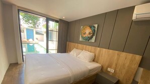 A bedroom with a wooden bed, a nightstand, a wall-mounted air conditioner, and a large window with a view of the outside. - Pamela Bali (Keroboken Kelod)