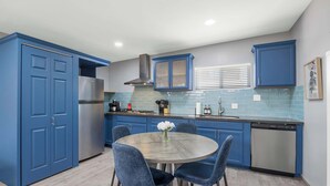 A kitchen with blue cabinets, a stainless steel refrigerator, a dishwasher, and a round table with chairs. - Broadway Casita - Remodeled Minutes from U of A (Tucson)