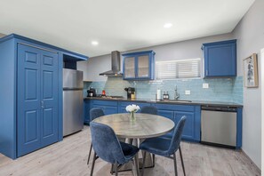 A kitchen with blue cabinets, a stainless steel refrigerator, a dishwasher, and a round table with chairs. - Broadway Casita - Remodeled Minutes from U of A (Tucson)