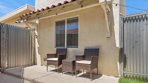 A patio with two wicker chairs, a window, and a metal gate. - Broadway Casita - Remodeled Minutes from U of A (Tucson)
