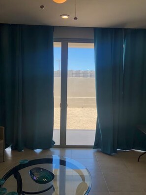 Ein Zimmer mit Glastisch, Blick durch eine Tür und Vorhängen.