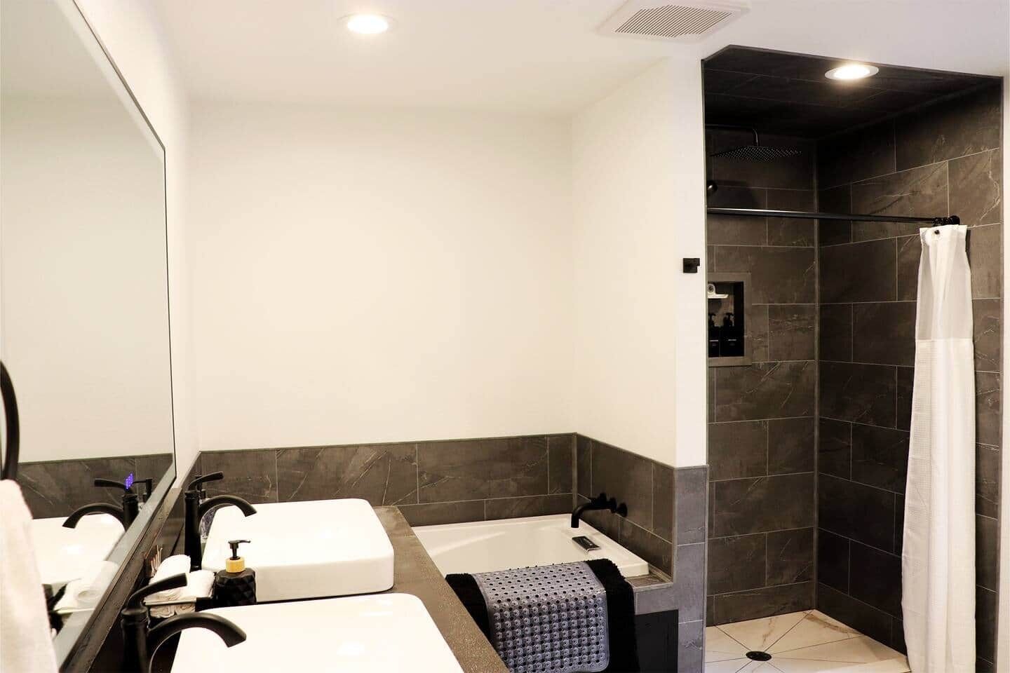 Une salle de bain avec deux lavabos, une douche et un miroir.