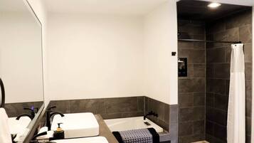 Une salle de bain avec deux lavabos, une douche et un miroir.
