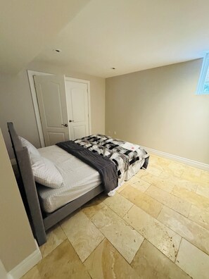 Um quarto com uma cama, uma porta e uma janela.