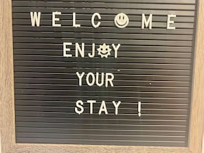 A welcome sign with the text 'WELCOME ENJOY YOUR STAY!' on a black background with horizontal lines.