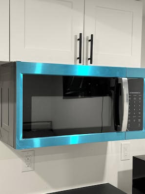 A kitchen with a microwave, cabinets, and a countertop.