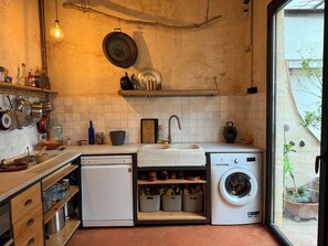 Een kleine keuken met een spoelbak, een wasmachine en een afwasschaal.