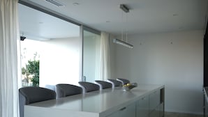 Una cocina moderna con encimera de mármol, sillas grises y un amplio ventanal.