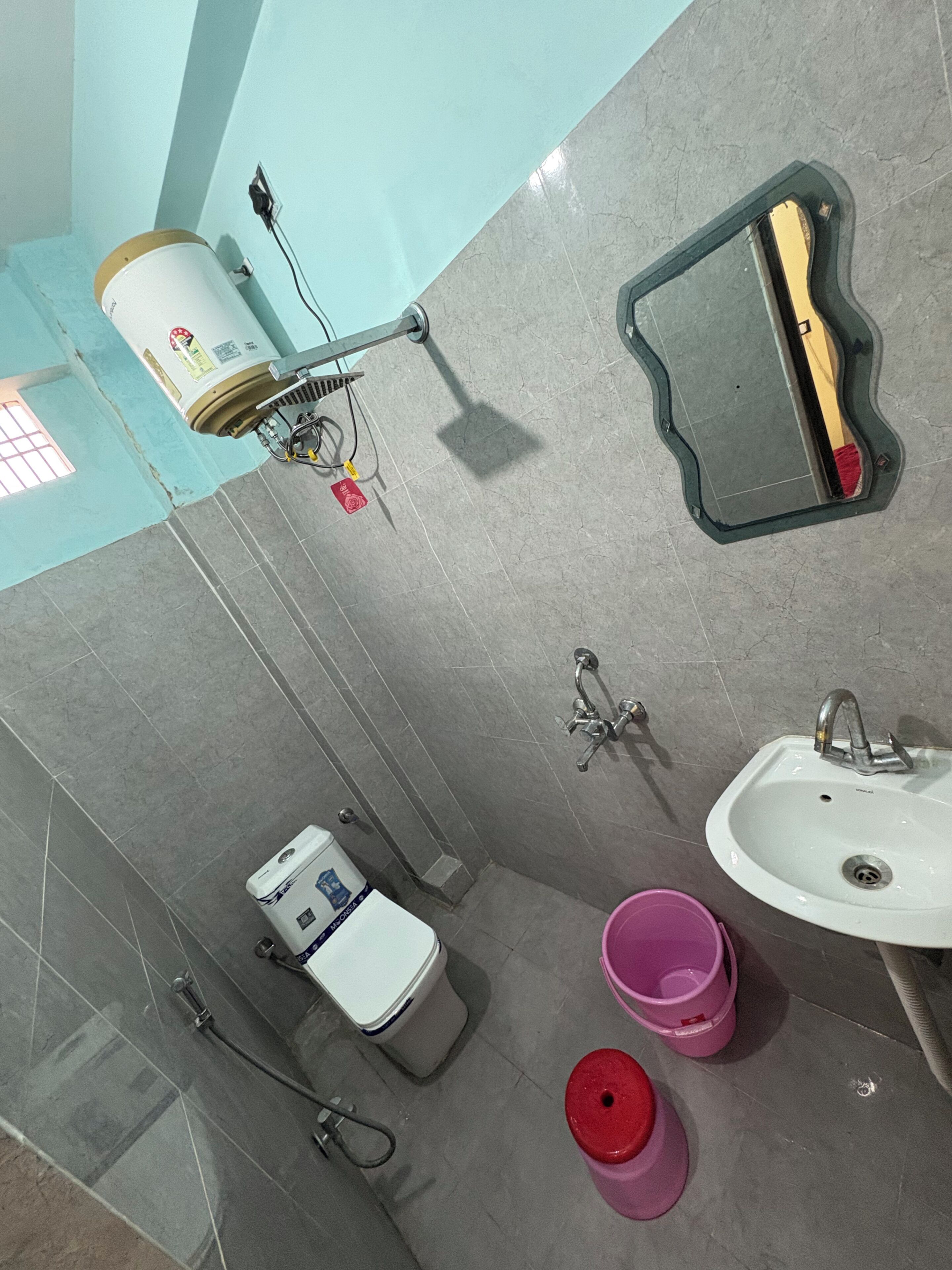 A bathroom with a toilet, sink, mirror, and shower.