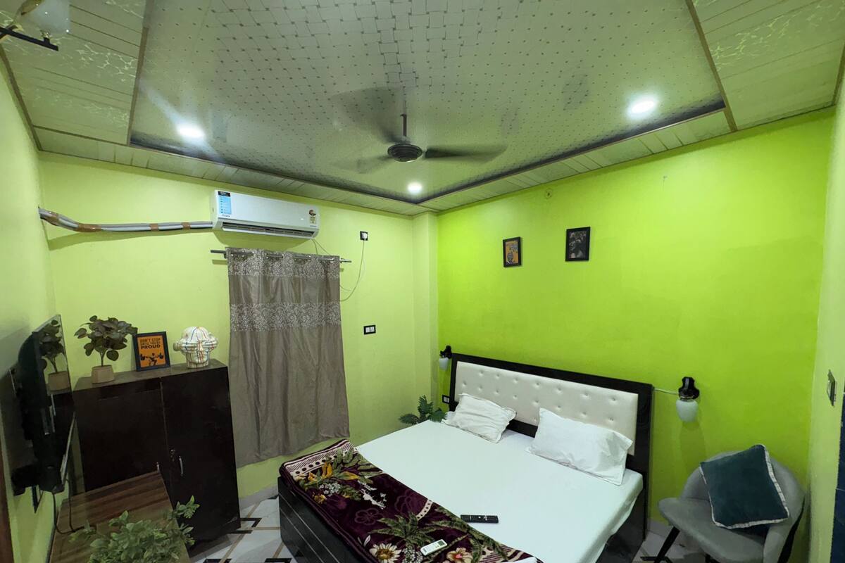 A bedroom with a bed, a desk, a chair, a ceiling fan, and a wall-mounted air conditioner.
