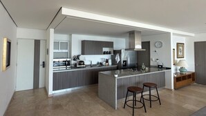 Eine moderne Küche mit einer zentralen Kochinsel, Barhocker und einem eingebauten Ofen.