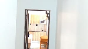 A hallway with a wooden floor and white walls, leading to a room with a wooden door and a view of a kitchen area. - Neo & Ruks Guest House Parow (Cape Town)