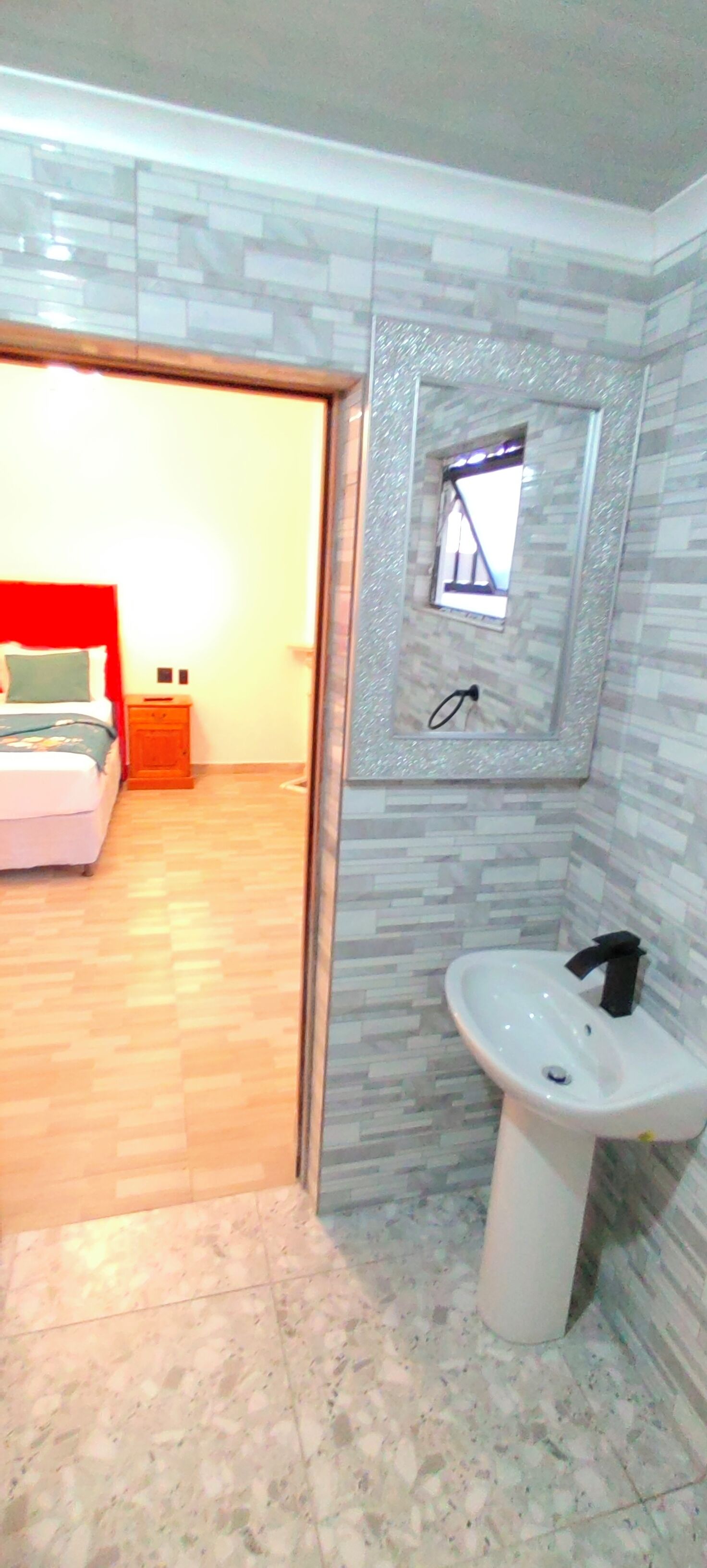 A bathroom with a sink, mirror, and tiled walls.