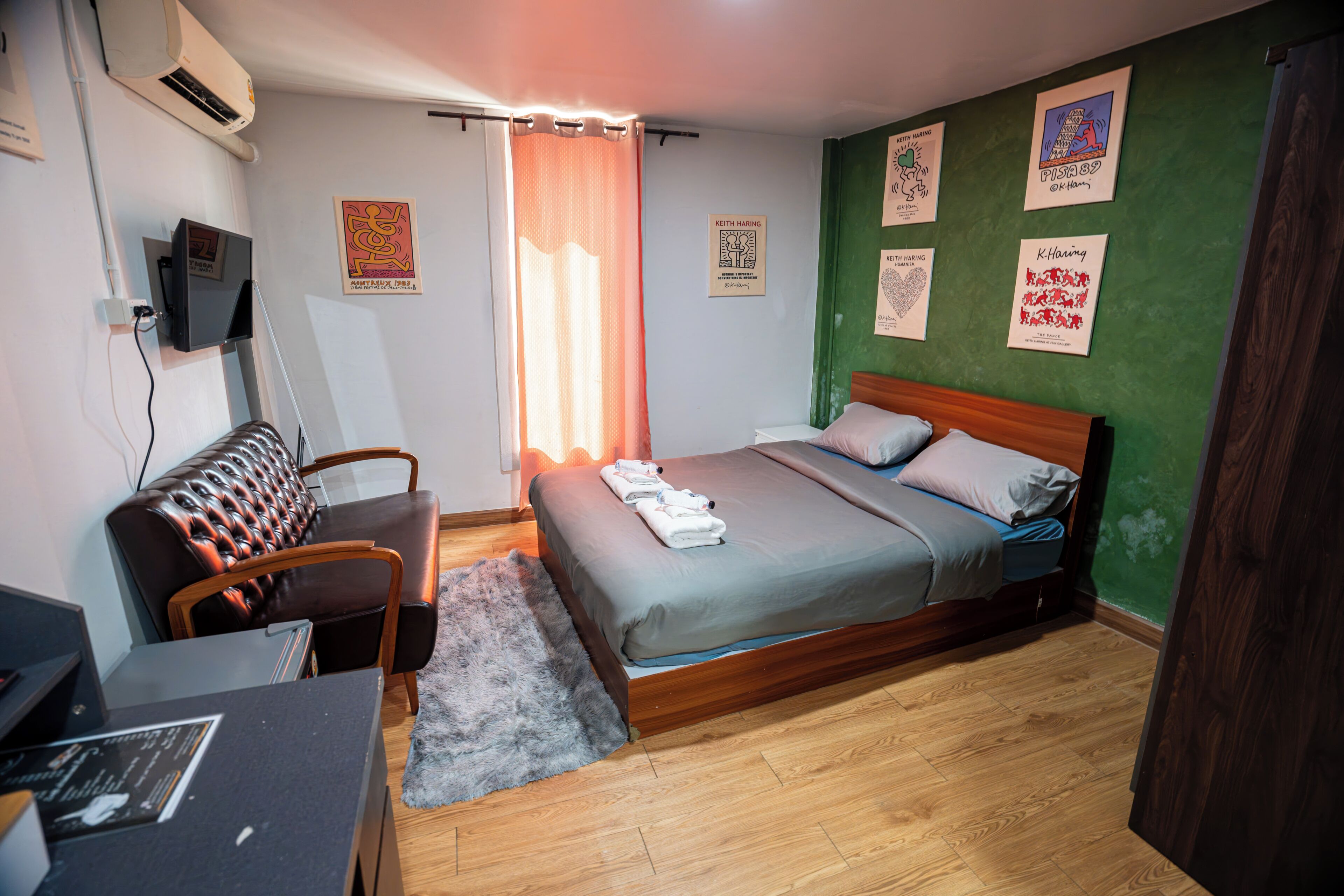 A bedroom with a bed, a desk, a chair, and a TV.