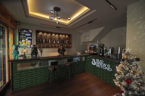 En bardisk med gröna kakelplattor, barstolar, en julgran och en skylt med texten ”Bud Brew & Beyond”.
