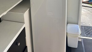 A compact kitchenette with a microwave, a small refrigerator, a kettle, and a trash bin. - Most Affordable Guesthouse in Hamilton? (Hamilton)