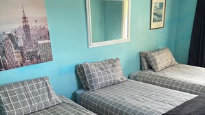 A hotel room with two beds, a cityscape poster, a mirror, and a framed picture on the wall. - Most Affordable Guesthouse in Hamilton? (Hamilton)