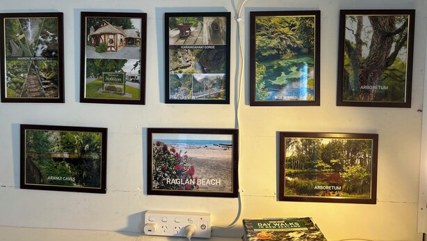 A wall with framed photographs of various natural landscapes and locations, including waterfalls, beaches, and caves. - Most Affordable Guesthouse in Hamilton? (Hamilton)