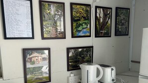 A room with a white desk, framed pictures on the wall, a kettle, a toaster, and a stack of books. - Most Affordable Guesthouse in Hamilton? (Hamilton)