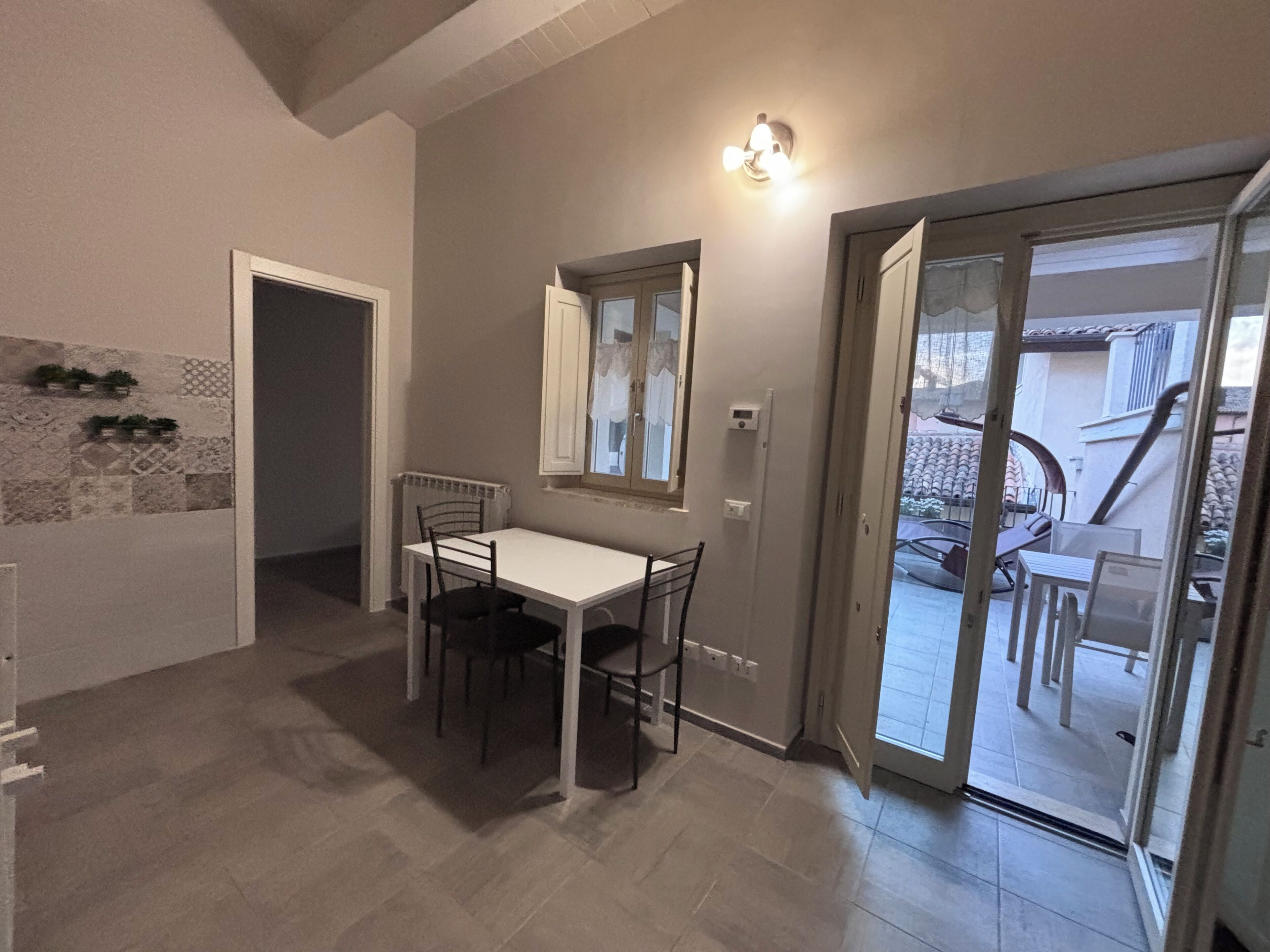 Un comedor con mesa y sillas, una ventana con vistas y una puerta que da a un patio exterior.