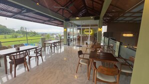 A spacious outdoor dining area with tables and chairs, a view of the countryside, and a restaurant with a sign reading 'SANER.' - Gorgeous 3-bedroom villa in cool Wonosobo for relaxing stays (Wonosobo)